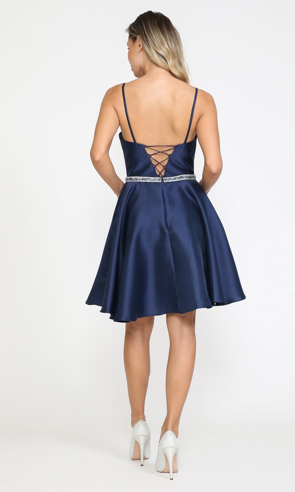 Woman in the Short Mikado Homecoming Dress 8420 with Pockets—navy blue, sleeveless, short with lace-up back and jeweled waistband—paired with white heels; a stylish party dress for under $150.